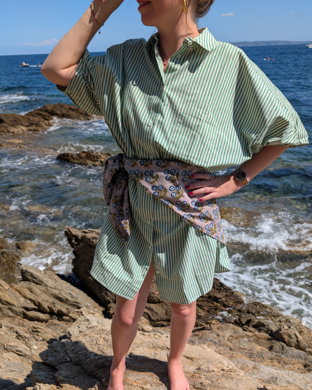 Foulard fleuri bleu pozé porté autour de la taille, en ceinture sur une robe de plage, une femme face à la mer